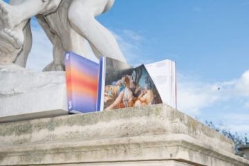 An incredible photograph of the New Society book in a stylized manner under a statue